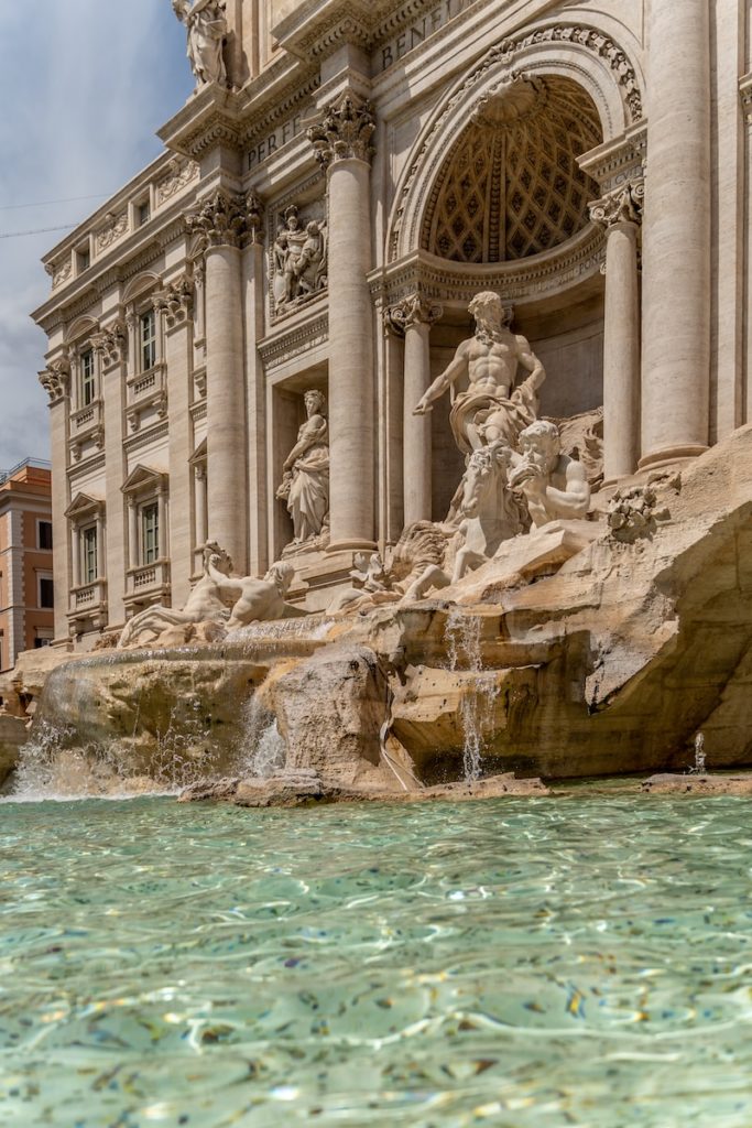 a fountain with statues in front of Trevi Fountain