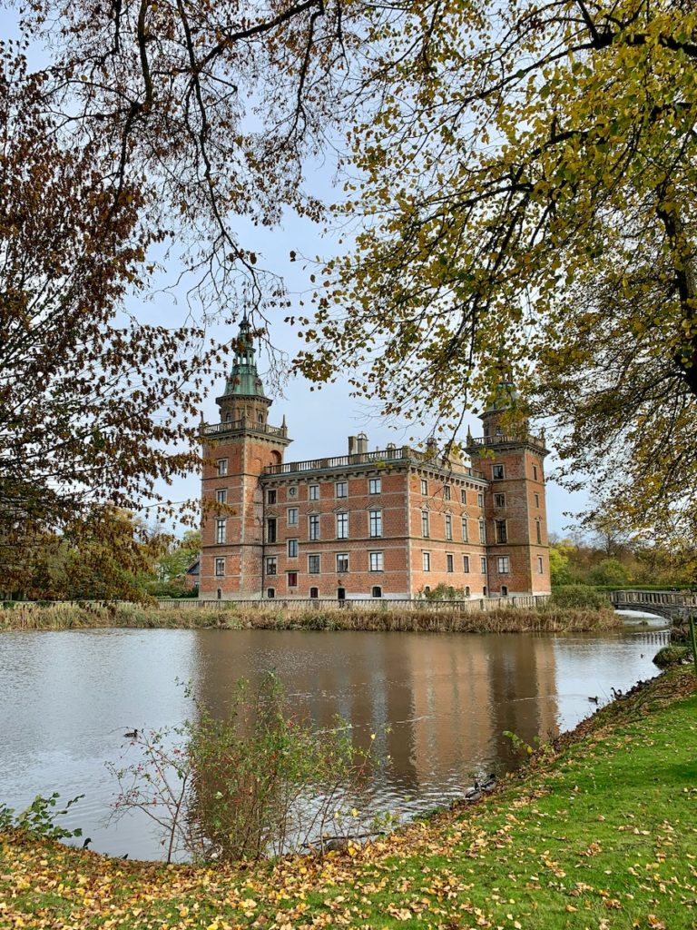 brown concrete castle and green leafed trees near body of water